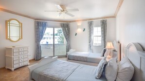 Un dormitorio con dos camas, un ventilador de techo, un aparador y una ventana con cortinas.