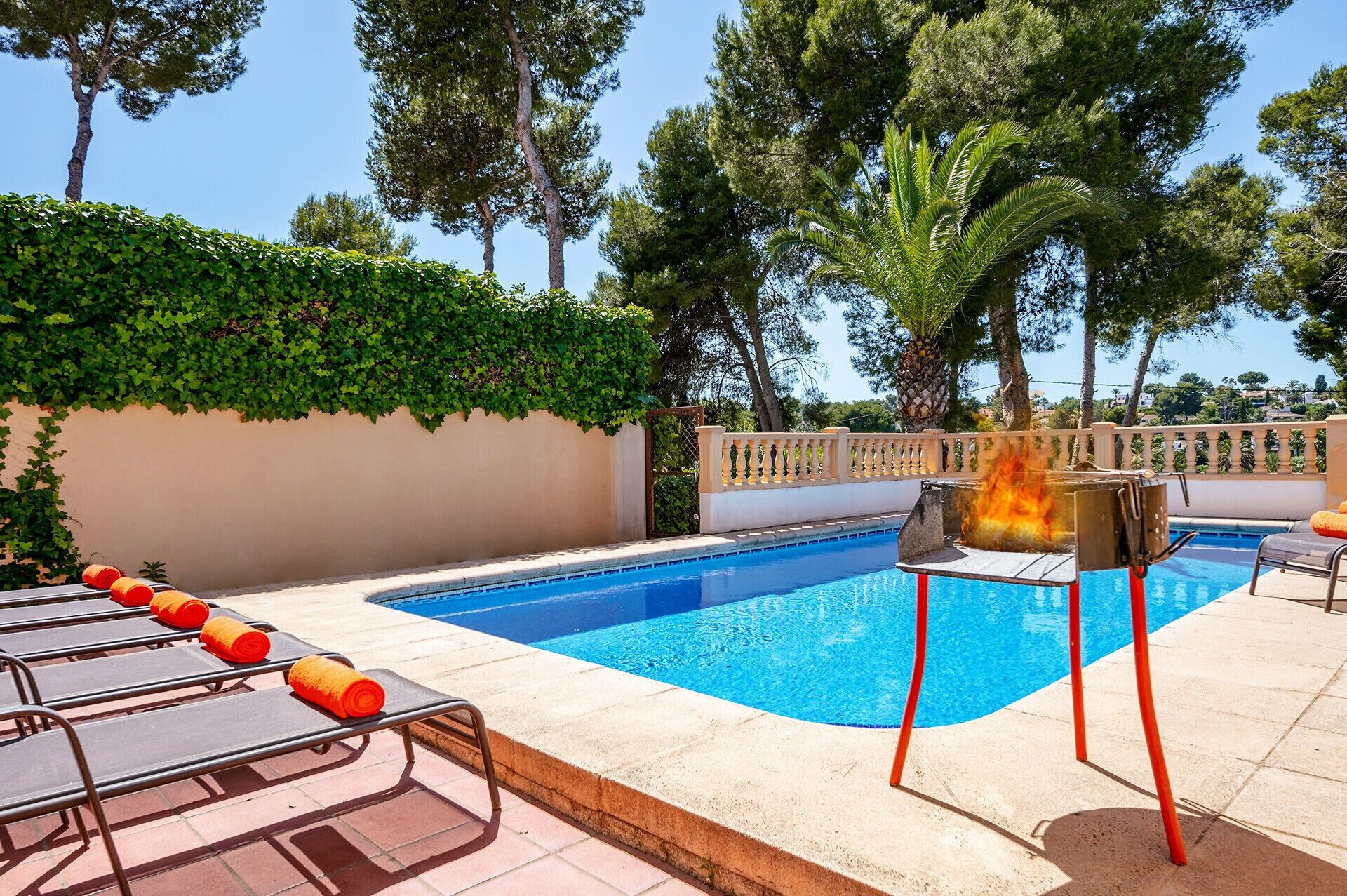 Une piscine avec un barbecue et des chaises longues.