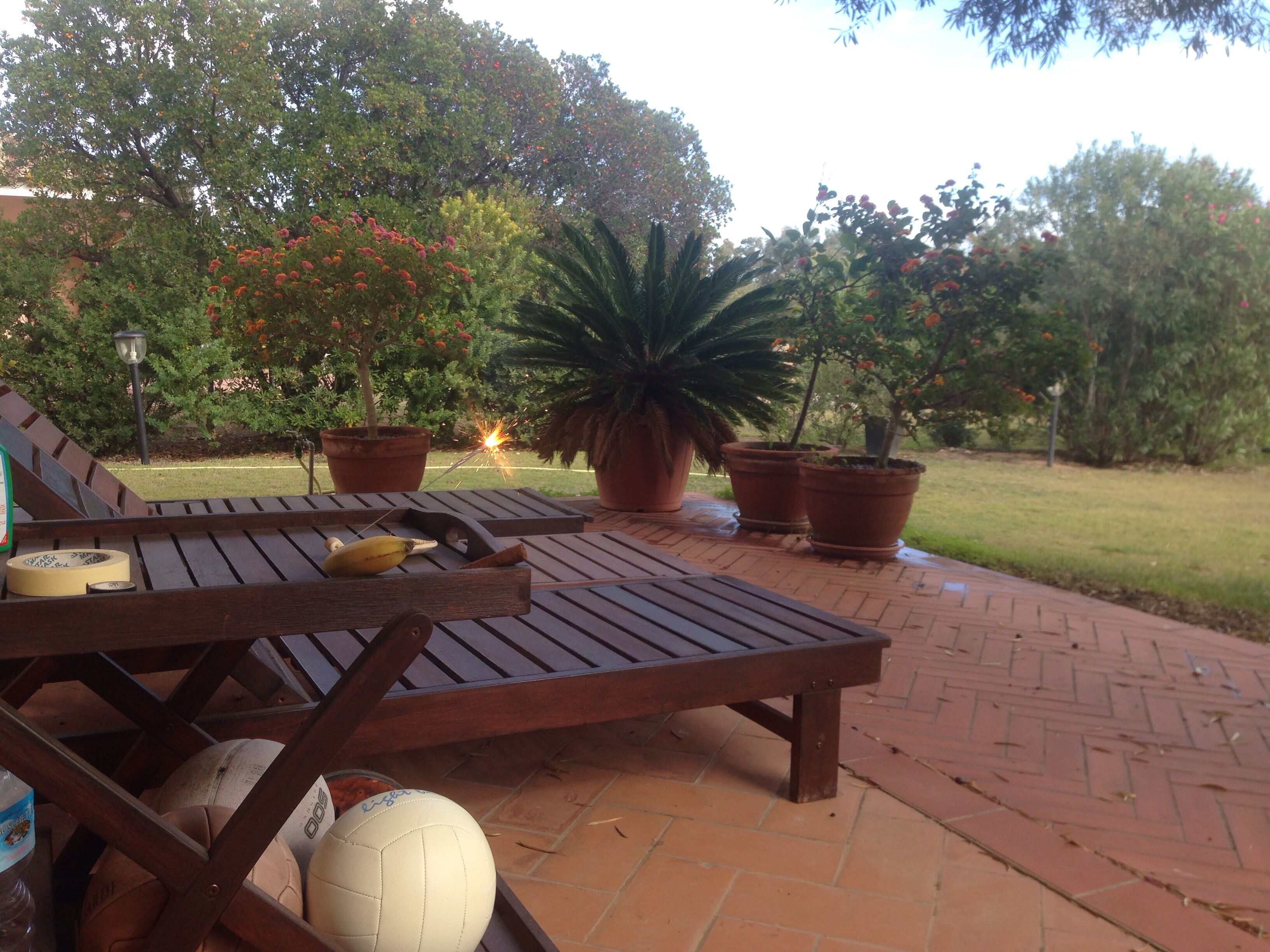 A patio with wooden furniture, a volleyball, and potted plants.