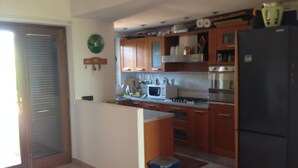 A kitchen with wooden cabinets, a black refrigerator, a microwave, and a stove.