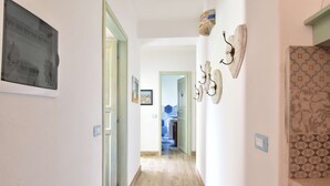 A hallway with wooden flooring, a framed picture on the left, and a decorative wall piece on the right. - Villa with 3 bedrooms and 2 bathrooms in residence (Aglientu)