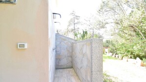 A stone-walled outdoor shower area with a stone floor, a wall-mounted light fixture, and a small electronic device on the wall. - Villa with 3 bedrooms and 2 bathrooms in residence (Aglientu)
