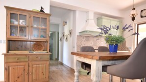 A dining area with a wooden table, two chairs, and a cabinet with glass doors. - Villa with 3 bedrooms and 2 bathrooms in residence (Aglientu)