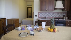 A dining area with a table set for breakfast, including plates, cups, and a fruit bowl.