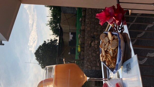 A table with a pitcher of orange juice, a plate with cookies, and a red flower.
