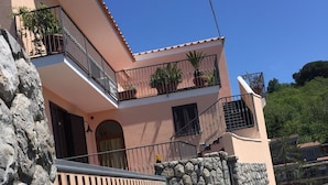 A two-story building with a stone wall and a wooden fence.