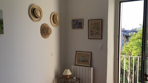 Ett sovrum med en säng, ett litet bord med en lampa, ett element och ett fönster med utsikt över grönområden.