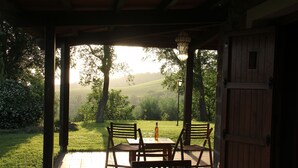 An outdoor patio with wooden chairs and a table, overlooking a lush green landscape. - Hilltop farmhouse with pool and sea view (pereta (GR))