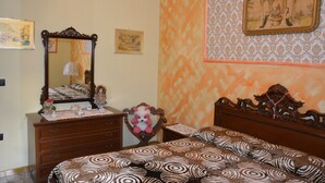 Una camera da letto con un letto di legno, una cassettiera, uno specchio e carta da parati decorata.