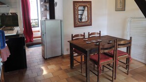 A compact kitchen with a refrigerator, a dining table with chairs, and a mirror on the wall. - Casal, very beautiful stone house in the wild steppe of the Causse (Campestre-Et-Luc)