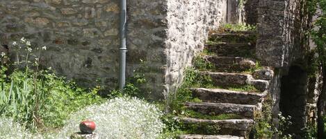 A stone staircase leading up to a building with a stone wall and a pipe running along it.