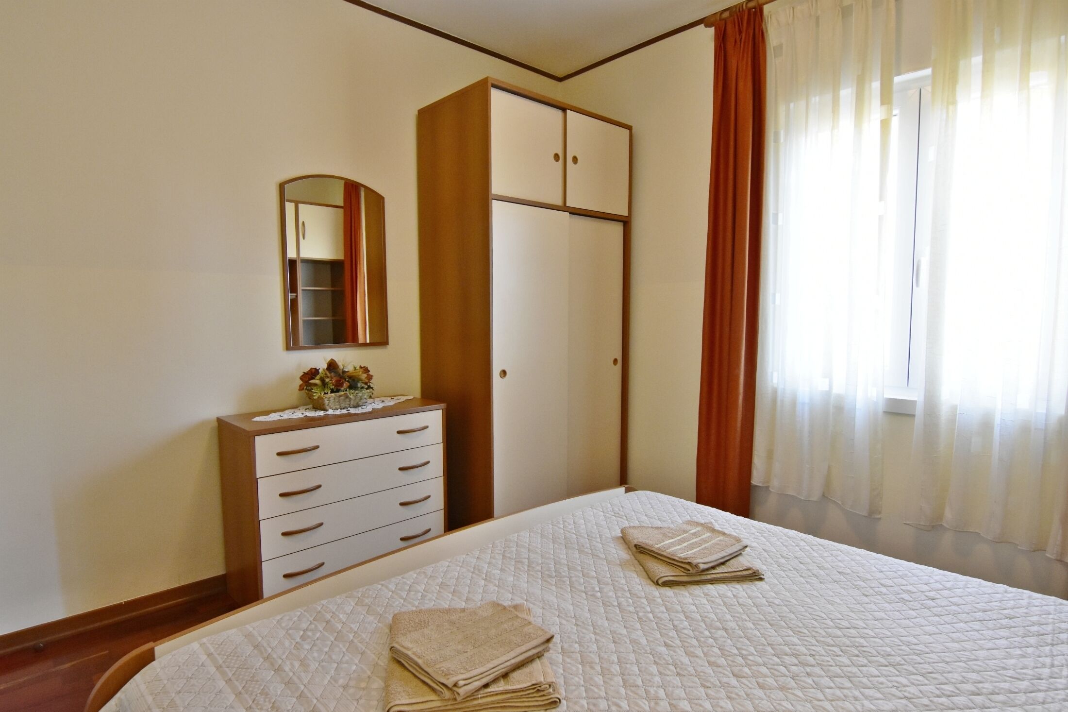 A bedroom with a bed, a dresser, a mirror, and a wardrobe.