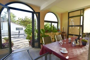 Un espace repas ouvert avec une table dressée pour deux personnes, agrémentée d’une nappe rouge et d’une bouilloire.