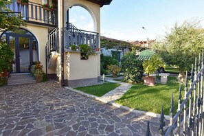 Une entrée dallée de pierres, agrémentée d’un balcon, de plantes en pot et d’une pelouse bien entretenue.