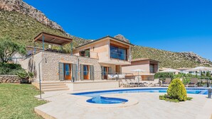 Ein modernes, zweistöckiges Haus mit Swimmingpool, Sitzgelegenheiten im Freien und einer Steintreppe.