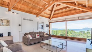 Ein geräumiges Wohnzimmer mit hoher Decke und großen Fenstern mit Blick auf die Landschaft.
