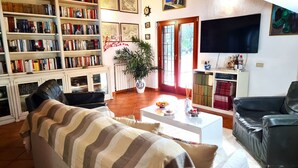 Un saló amb un sofà a ratlles, una taula de centre, una biblioteca, un televisor i una planta en test.