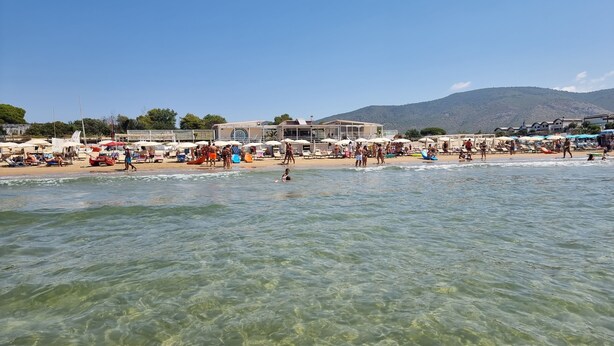 Una platja amb aigua cristal·lina, ombrel·les i gent.