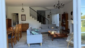 A spacious living area with a staircase, a dining set, and a fireplace.