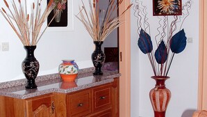 A room with a wooden cabinet, two vases with decorative plants, a mirror, and a chair. - Villa De Rêve with Pool XXL (Fundao)