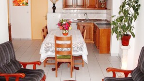 A dining area with a table set for four, a kitchen with wooden cabinets, and a potted plant. - Villa De Rêve with Pool XXL (Fundao)