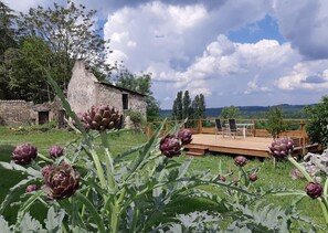 Un edificio rústico de piedra con una terraza de madera y zona de estar al aire libre.