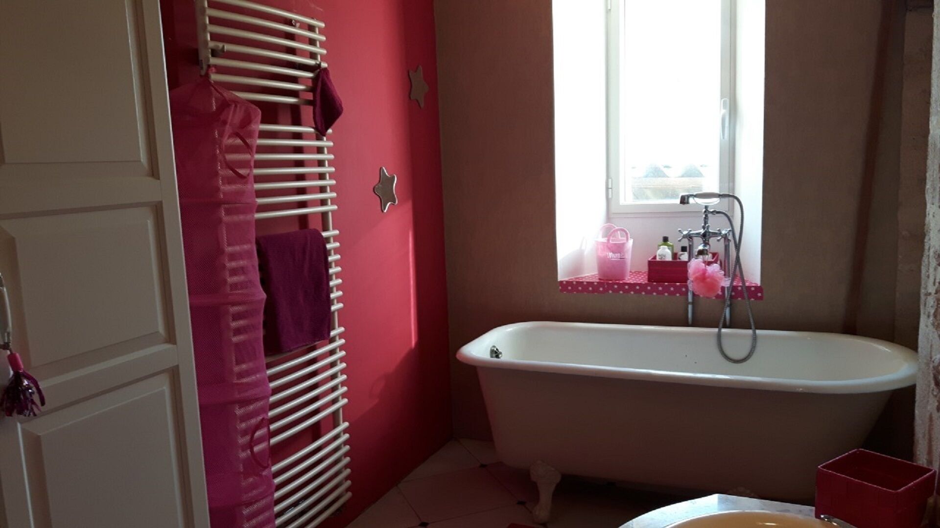 Un bagno con una vasca da bagno bianca, una finestra vista e un portasciugamani rosa.