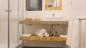 Un bagno con cabina doccia in vetro, un mobile bagno in legno con lavabo e uno specchio con cornice in legno.