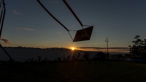 Altalena con struttura in metallo e sedile, affacciata su uno specchio d'acqua al tramonto.