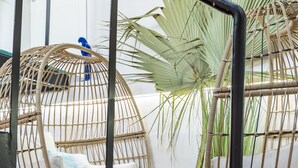 A modern outdoor seating area with wicker chairs, a small table, and a birdcage.