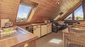 A cozy attic-style room with a kitchen, dining area, and seating space. - Studio apartment with sea view (Grömitz)