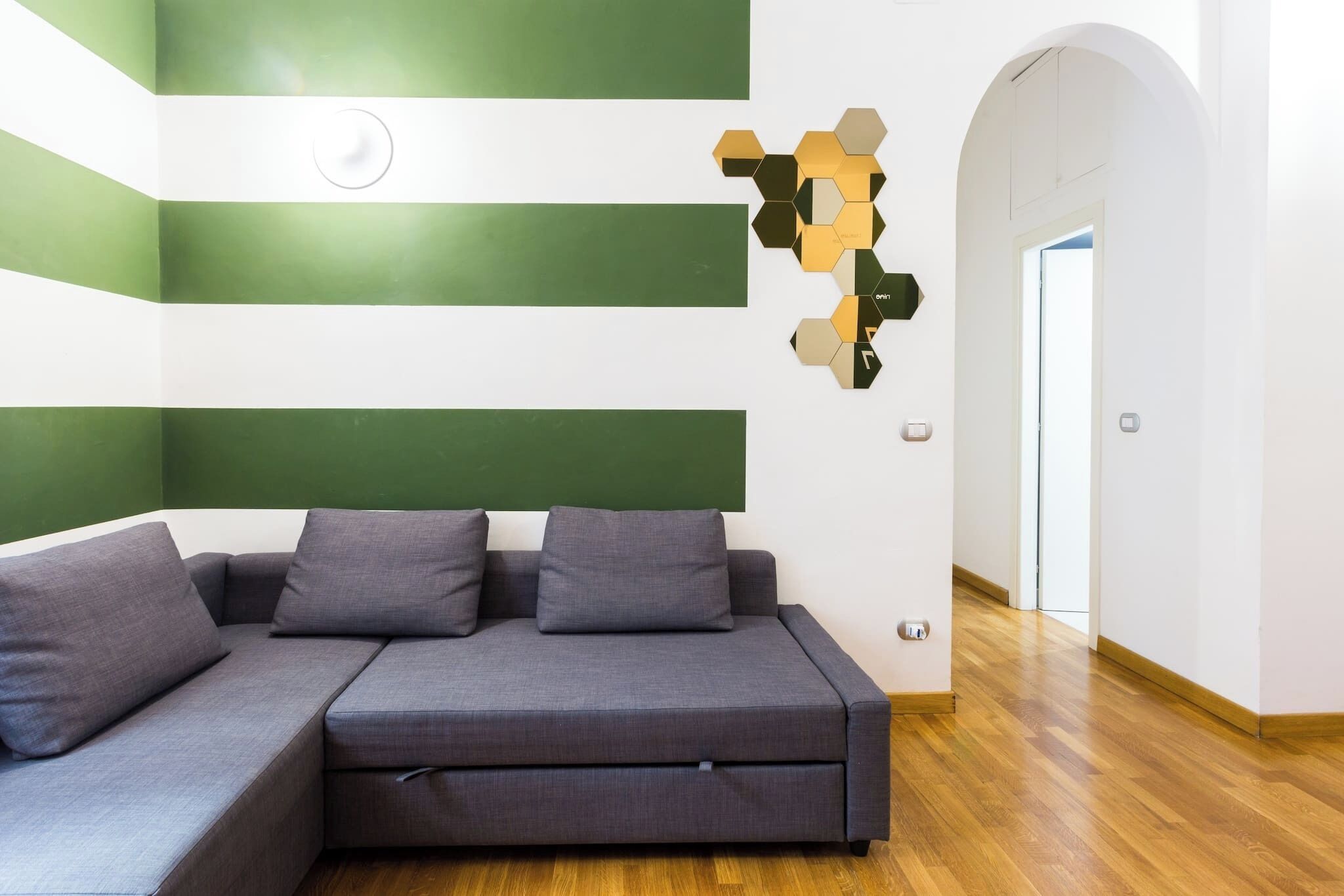 Una sala de estar moderna con un sofá seccional, una obra de arte geométrica en la pared y suelo de madera.