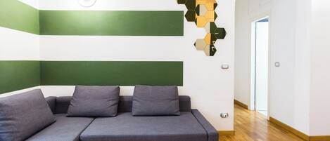 Una sala de estar moderna con un sofá seccional, una obra de arte geométrica en la pared y suelo de madera.