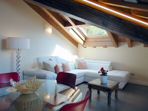 Een gezellige woonkamer met een witte bank, rode stoelen, een glazen salontafel en een houten salontafel.