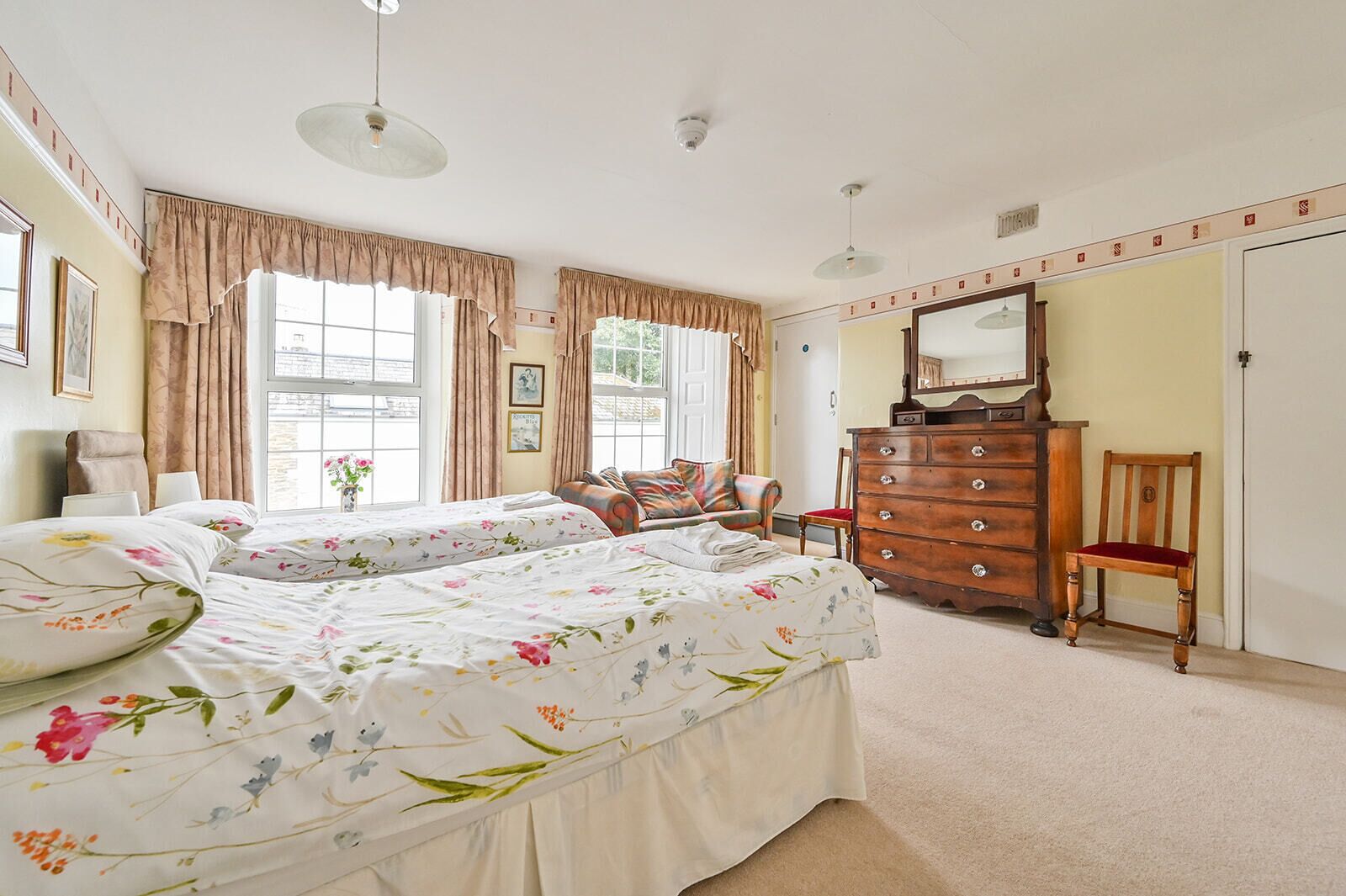 A bedroom with two beds, a dresser, a chair, and a mirror.