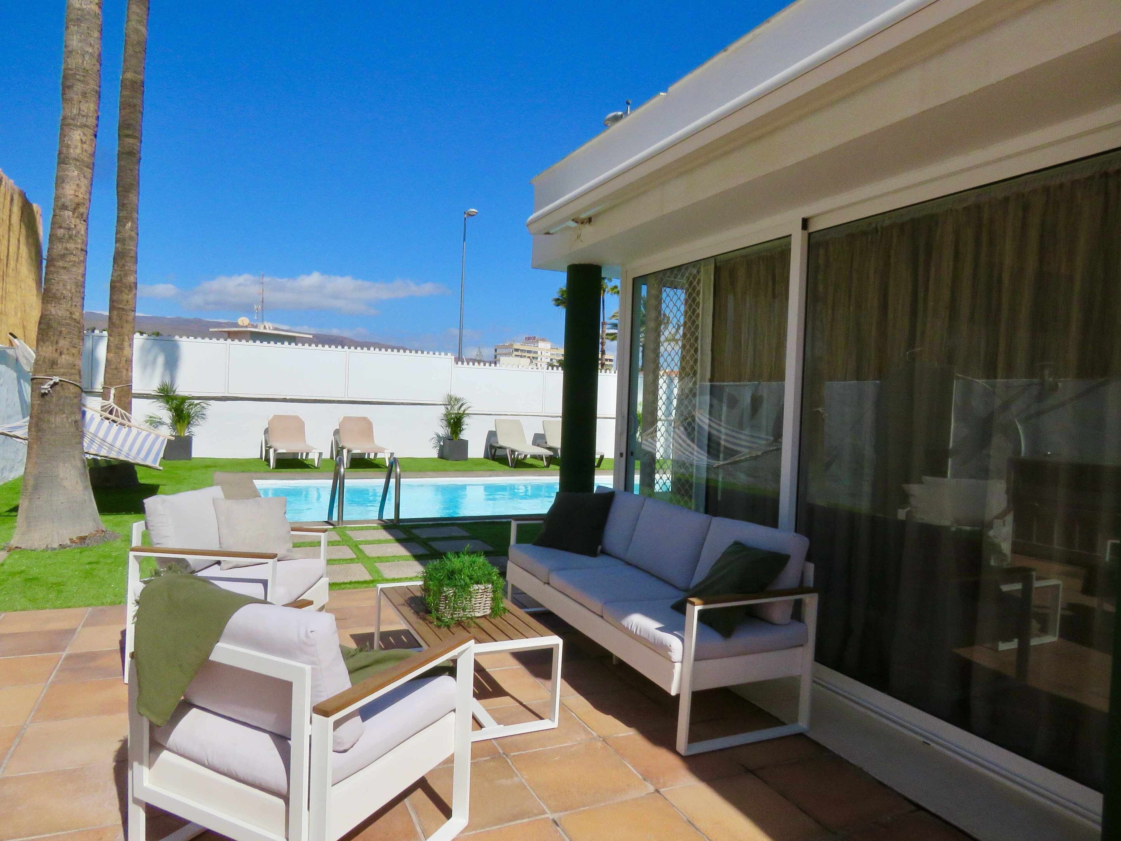 Une terrasse avec une piscine, du mobilier d’extérieur et une vue sur l’espace piscine.