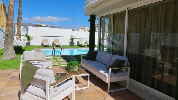 Eine Terrasse mit Pool, Gartenmöbeln und Blick auf den Poolbereich.