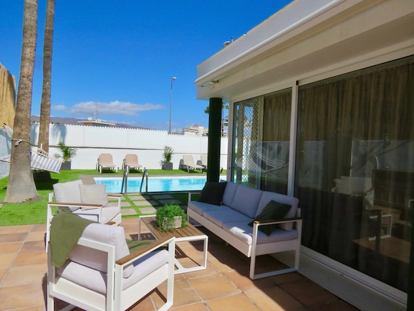 A patio with a pool, outdoor furniture, and a view of the pool area.