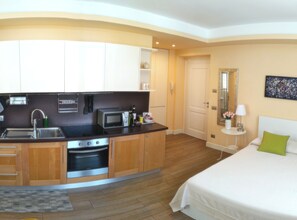 A modern hotel room with a kitchenette, a bed, and a bathroom.