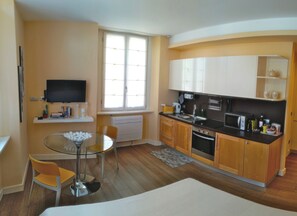 Een compacte keuken met een eethoek, een flatscreen-tv en een raam voor natuurlijk licht.