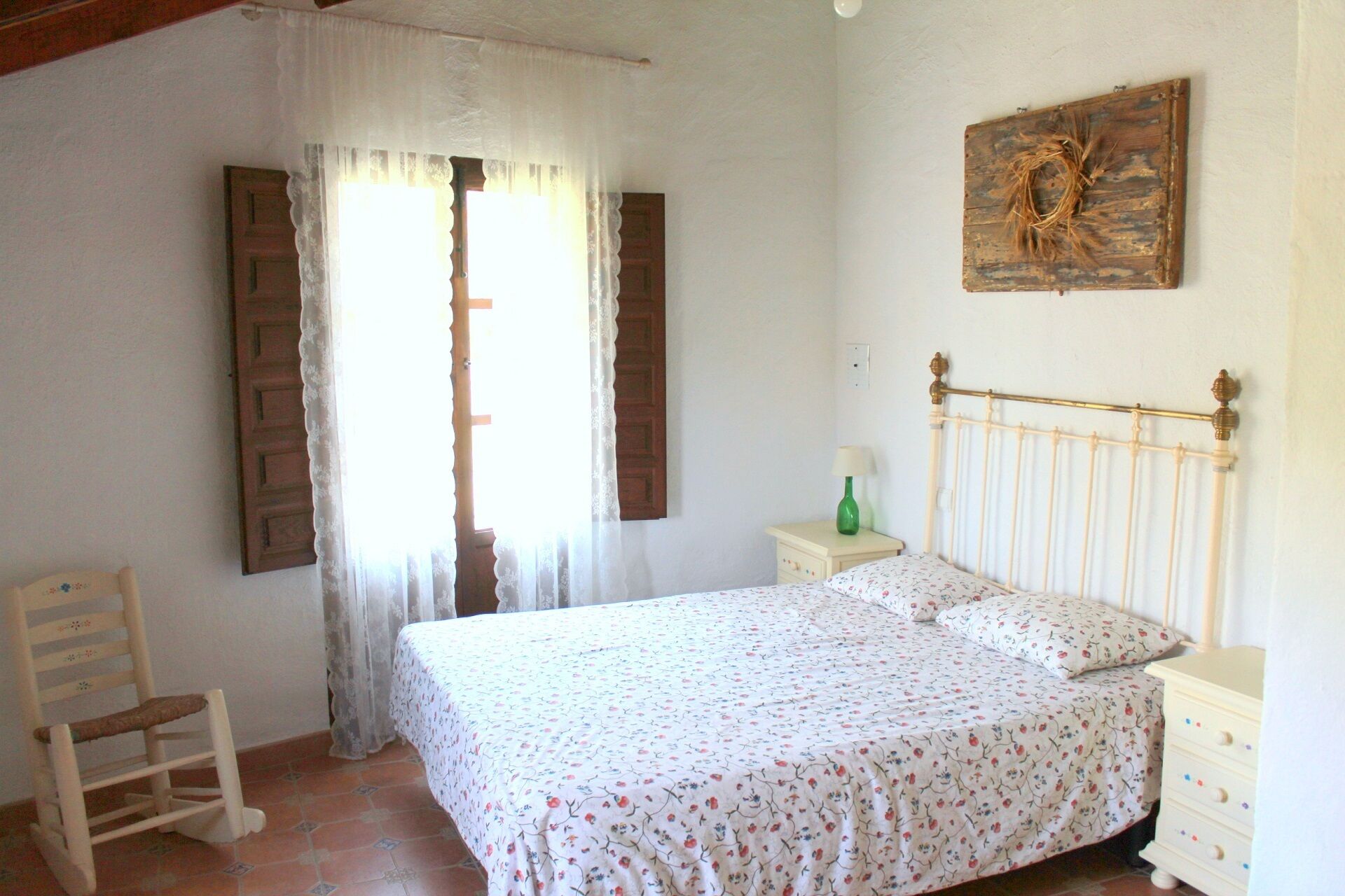 Une chambre à coucher comprenant un lit, une chaise, une table de chevet et un tableau accroché au mur.