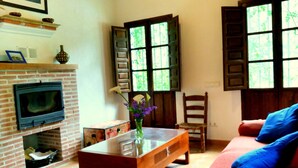 Sala de estar com lareira, sofá, mesa de centro e janela com persianas.