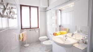 A modern bathroom with a toilet, bidet, sink, and a large mirror. - APPARTAMENTI MARCIANA MARINA - APPARTAMENTO L'EDERA (Marciana Marina)