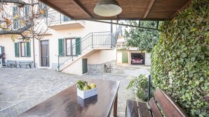 A courtyard with a wooden table, benches, and a covered area with a hanging light fixture. - APPARTAMENTI MARCIANA MARINA - APPARTAMENTO L'EDERA (Marciana Marina)