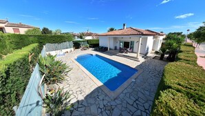A swimming pool with stone tiles, a covered patio, and a small building with a tiled roof. - 0533 Villa Laura Poblets (Denia)