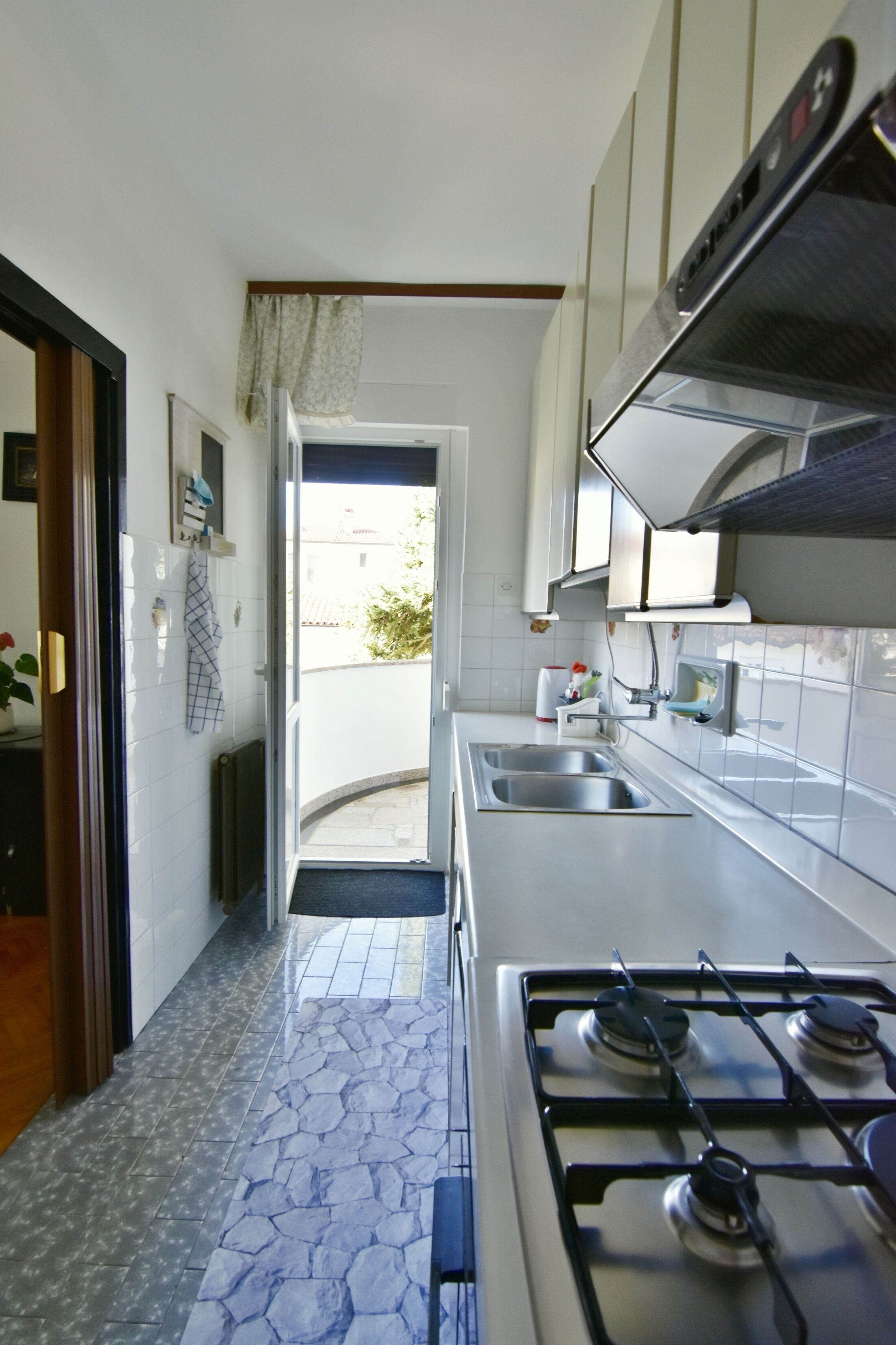 A modern kitchen with a gas stove, two sinks, and a view to the outside.