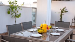 A dining table set outdoors with chairs, a bottle of orange juice, and a bowl of fruit. - Great penthouse in the center of Córdoba (Córdoba)