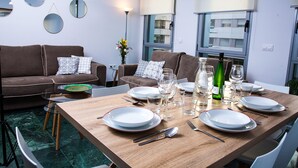 A dining area with a wooden table set for four, surrounded by a brown sofa with patterned cushions. - Great penthouse in the center of Córdoba (Córdoba)