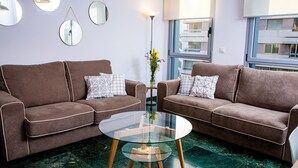 A modern living room with two brown sofas, a glass coffee table, and a vase with flowers. - Great penthouse in the center of Córdoba (Córdoba)