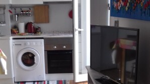 Una cocina compacta con lavadora, horno y televisor de pantalla plana.